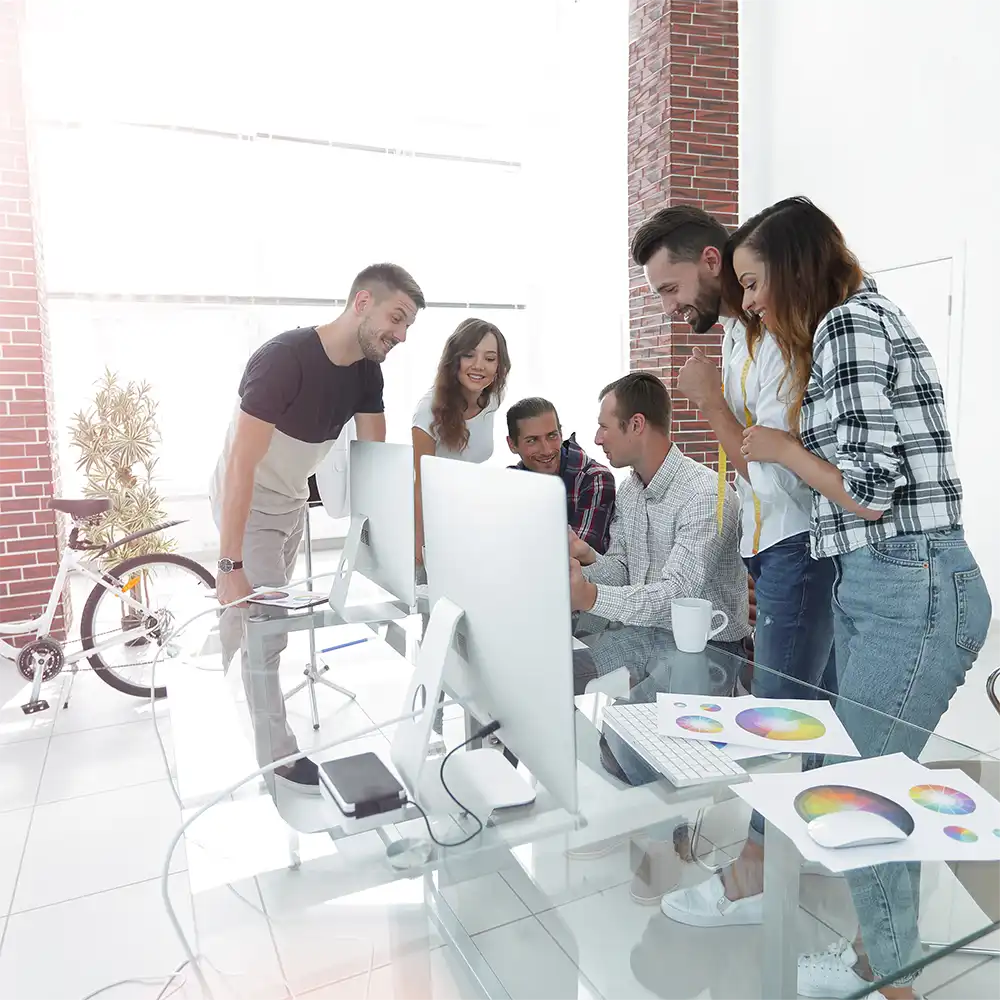 Gruppe junger Arbeitskollegen vor einem Computer diskutieren neue Ideen in einem Büro einer Agentur